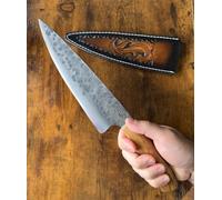 Faca de Chef artesanal em Aço carbono forjado, lâmina inteiriça com acabamento martelado, cabo de madeira de oliveira e com bainha de pele genuína.